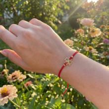 Гривна с червен конец и 14 карата златен елемент детелинка Гривна с червен конец и 14 карата златен елемент детелинка