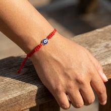 Гривна с червен конец и златен елемент синьо око