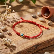 Гривна с червен конец и златен елемент синьо око