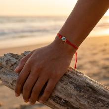 Гривна с червен конец и златен елемент синьо око