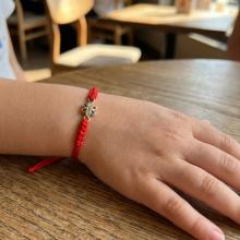 Гривна с червен конец и златен елемент цвете